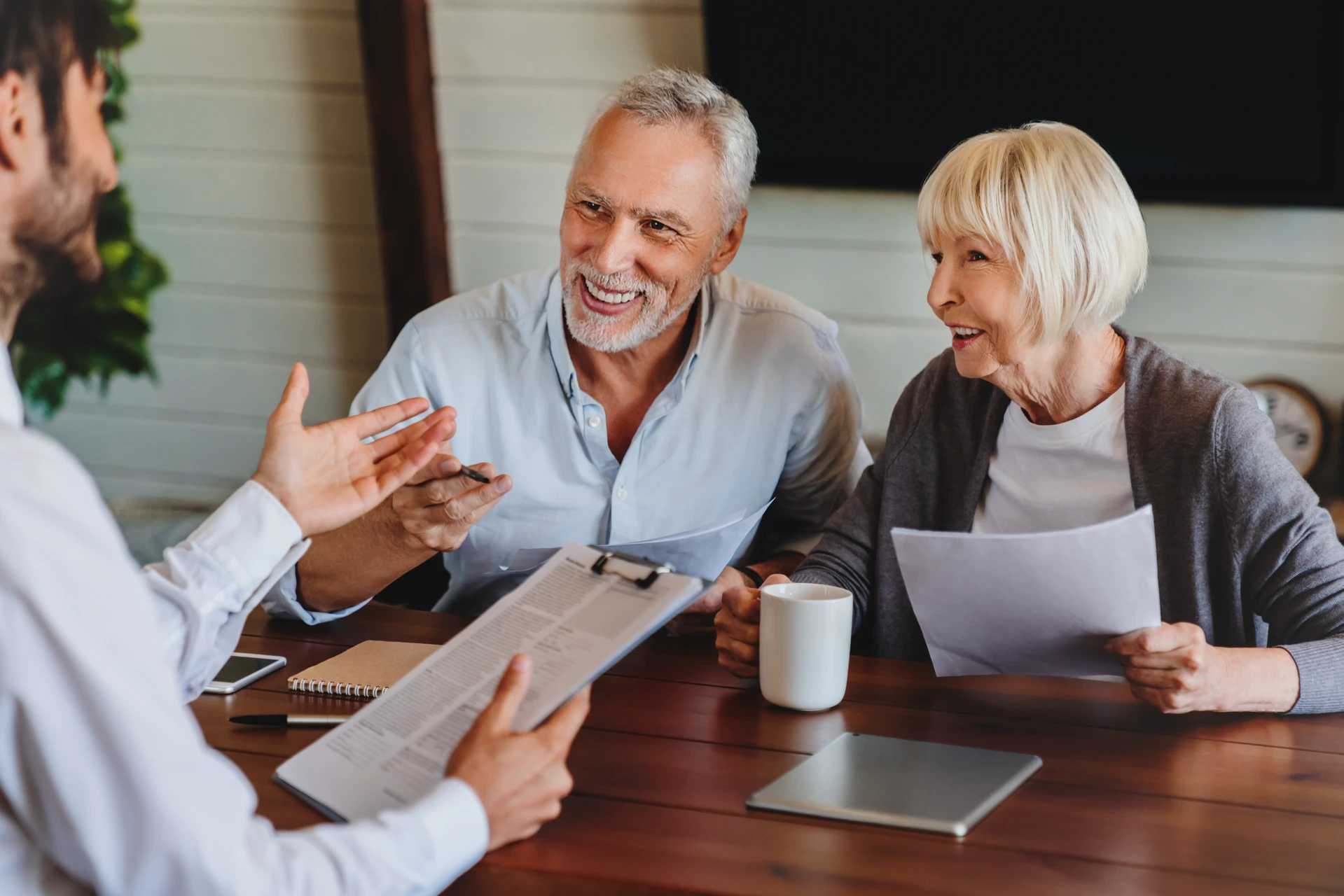 Agent d'assurance consultant un couple familial mature, discutant de l'assurance-maladie, signant un contrat de prêt hypothécaire de retraite à domicile, calculant les fonds, les investissements, l'épargne