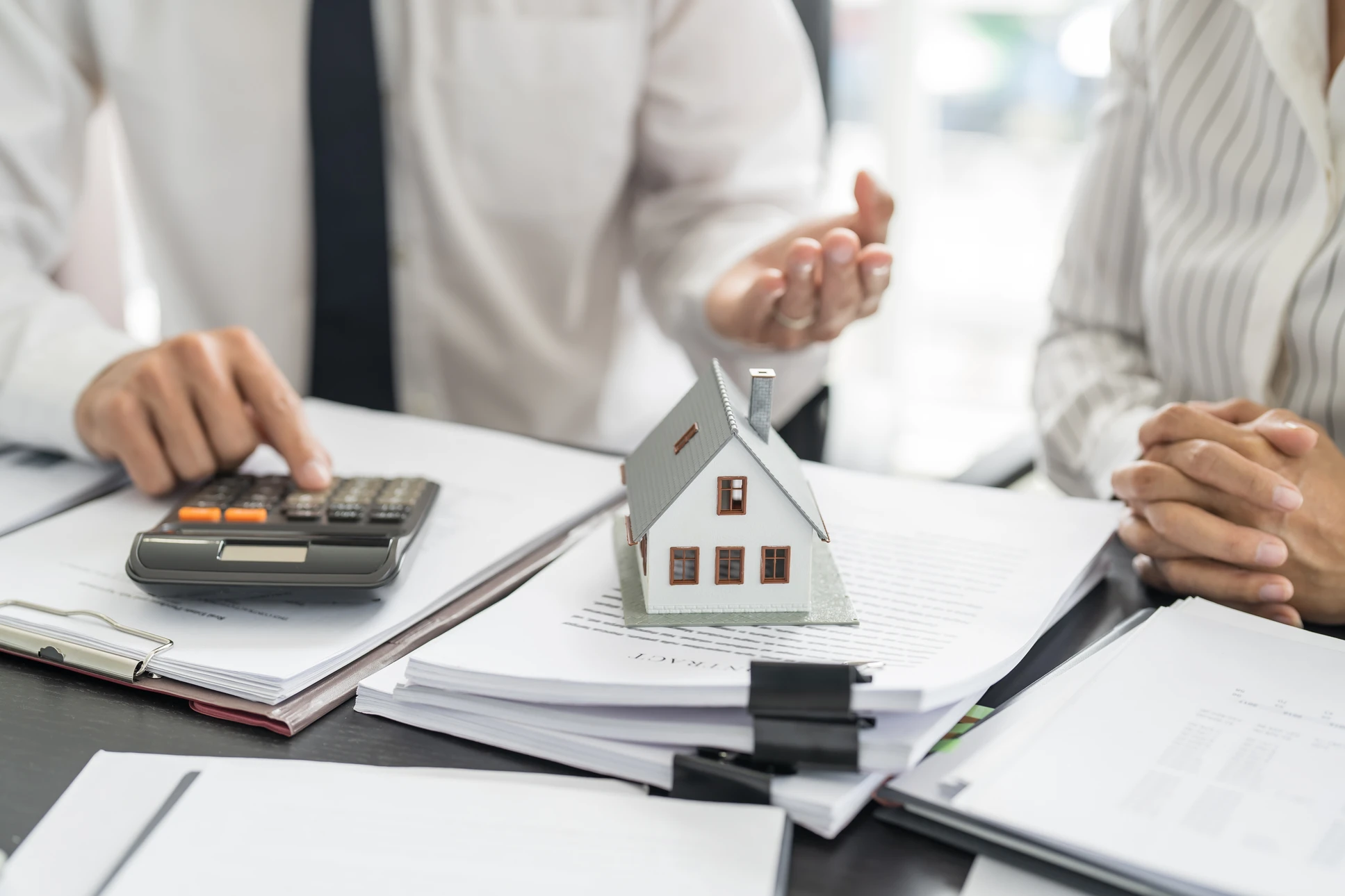 Agent d'assurance consultant un couple familial mature, discutant de l'assurance-maladie, signant un contrat de prêt hypothécaire de retraite à domicile, calculant les fonds, les investissements, l'épargne