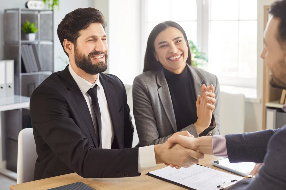 Réunion professionnelle dans bureau moderne avec conseiller financier en costume-cravate face à couple de clients seniors