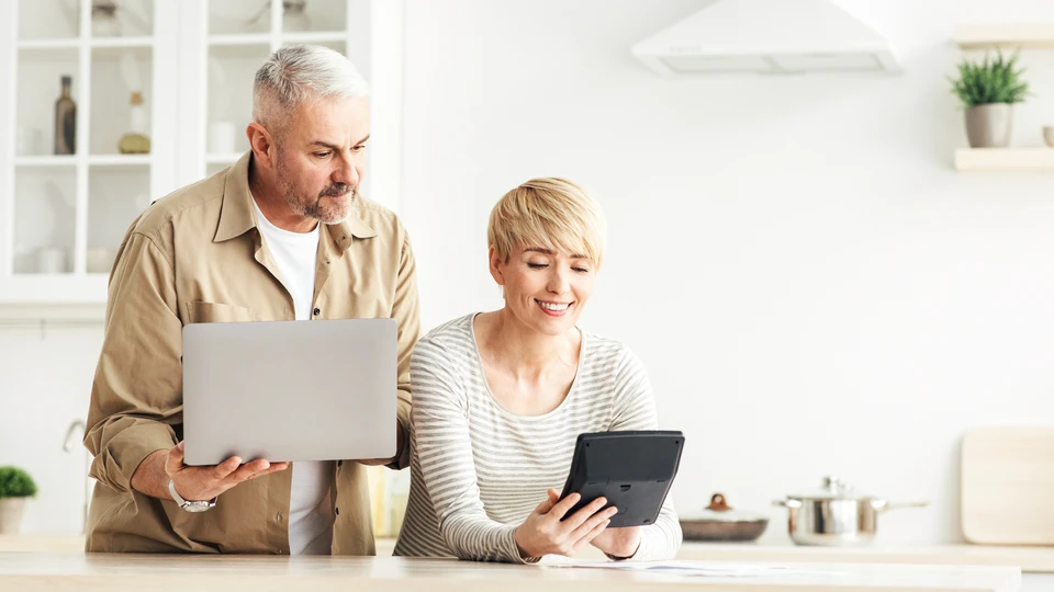 Réunion professionnelle dans bureau moderne avec conseiller financier en costume-cravate face à couple de clients seniors