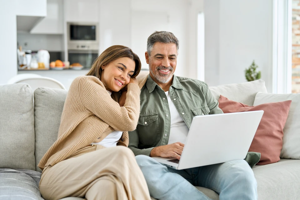 Couple souriant assis côte à côte face à un professionnel lors d'un rendez-vous de conseil